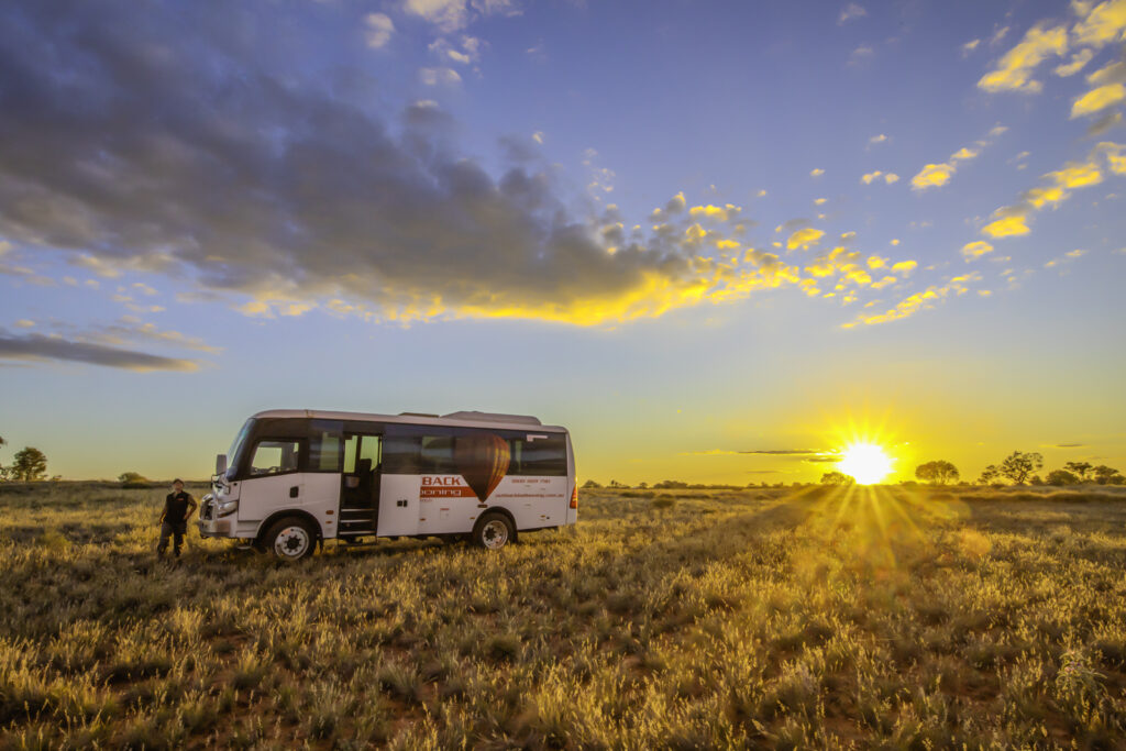 Experience the magic of an early morning in the Australian outback with the Outback Ballooning bus arriving to pick up passengers and crew after a breathtaking balloon flight. Set against the stunning backdrop of the Alice Springs landscape, this adventure combines the beauty of nature with the thrill of flight. Perfect for nature lovers and adventurers alike!